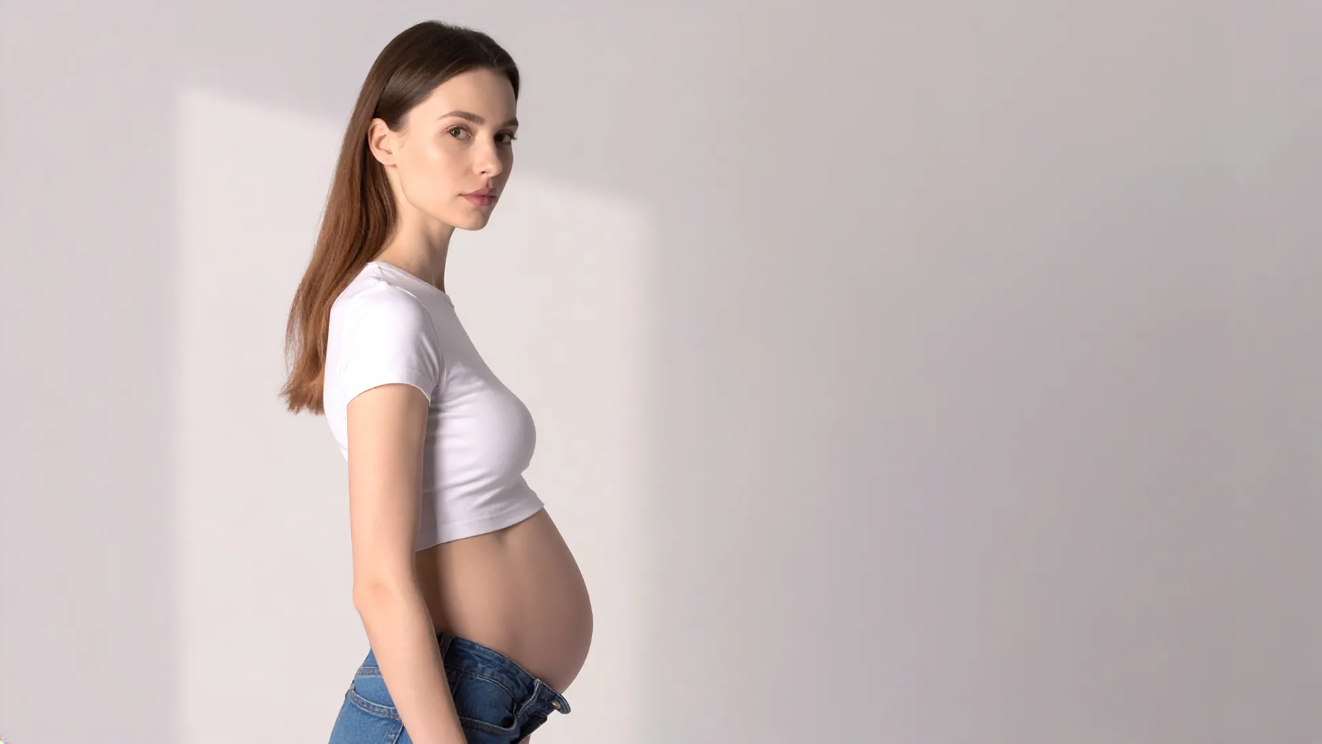 Grūtniece sānu pozā ar roku uz vēdera