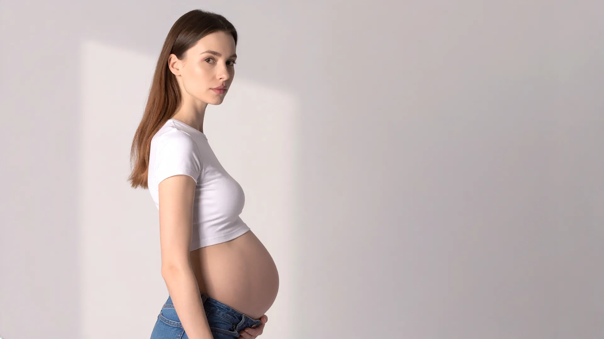 Grūtniece sānu pozā ar roku uz vēdera