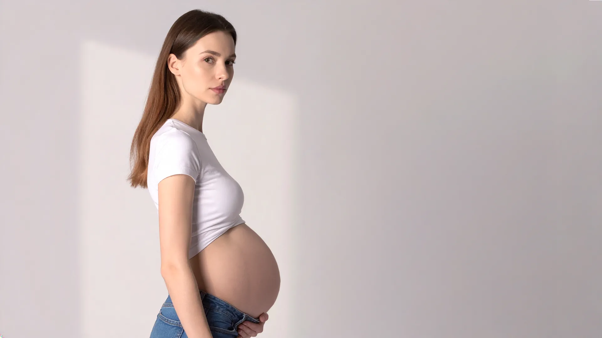 Grūtniece trešajā trimestrī stāv sānu pozā